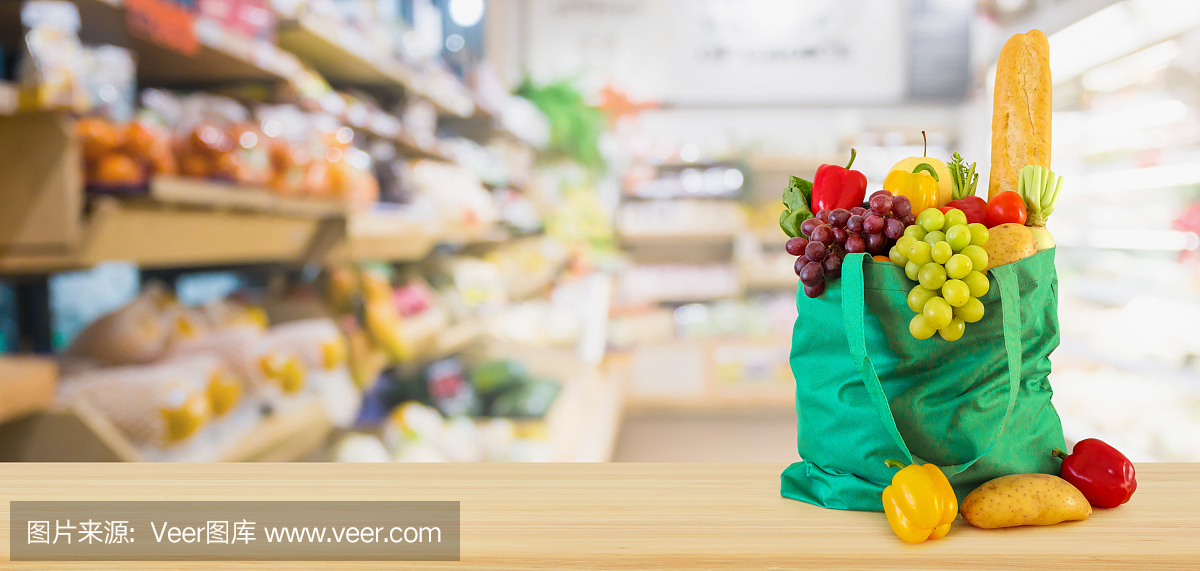 新鲜的水果和蔬菜在可重复使用的绿色购物袋木质桌面上超市杂货店模糊散焦背景与散焦光